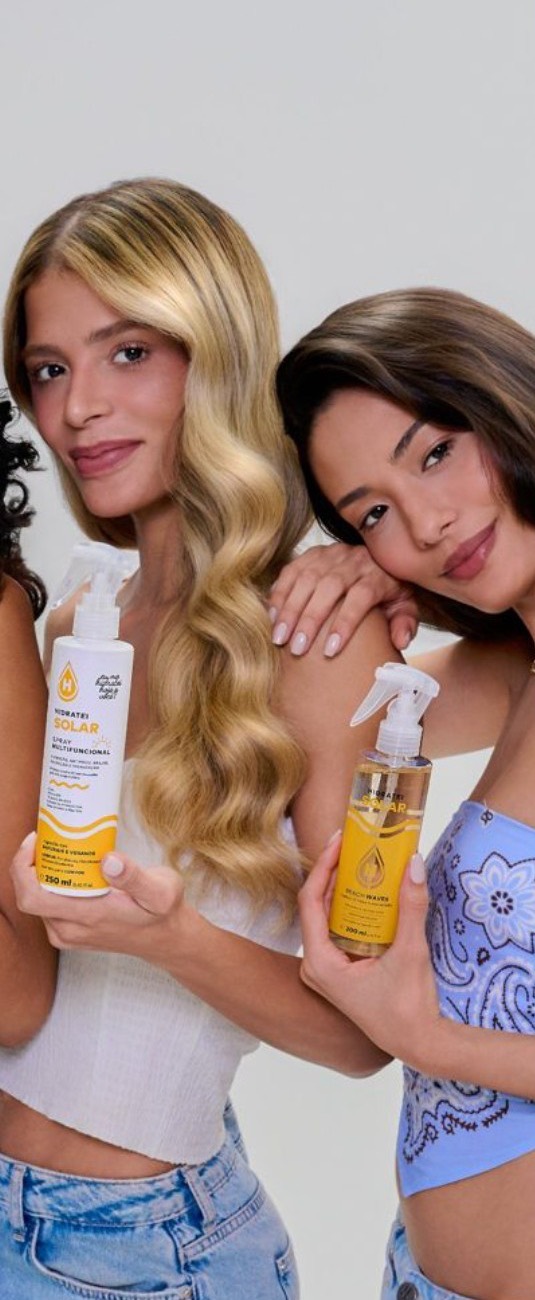 Duas criadoras sorrindo, cada uma com um spray Hidratei na mão